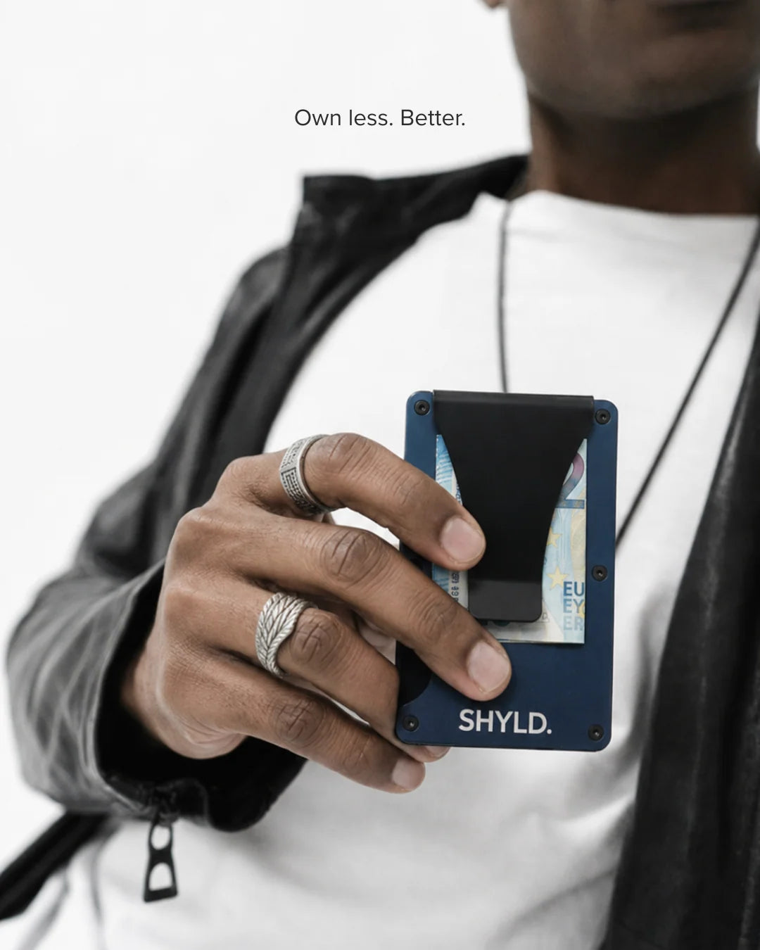Porte-cartes SHYLD bleu en aluminium avec clip à billets, tenu en main.